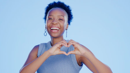 Face, heart hands and black woman with support, feedback and wellness on a blue background....