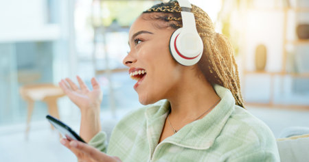 Phone, singing and happy woman on music headphones in home living room. Smartphone, dance and...
