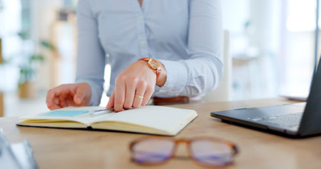Employee, planning and notes in journal with desk, laptop and business schedule, agenda or administration reminder. Office, notebook and woman writing in diary with ideas for receptionist to rememberの写真素材
