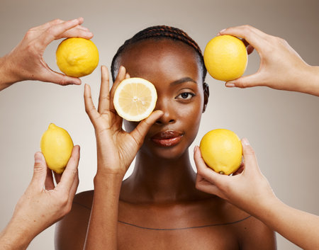 Hands, lemon and natural beauty, black woman in portrait for wellness and sustainable skincare on brown background. Health, nutrition and fruit, dermatology and vegan product with vitamin c in studioの写真素材