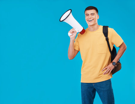 Portrait, megaphone and man with a smile, announcement and promotion on a blue background. Person, activist and happy model with a bullhorn, change and happiness with justice, speech and mockup spaceの写真素材