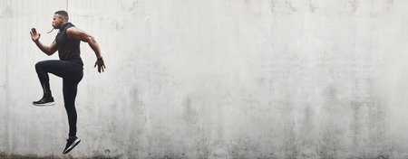 Wall, mockup and fitness man with stretching jump in a city for training, cardio or morning workout. Space, exercise and male athlete with energy, jumping and sports, freedom and body performanceの写真素材