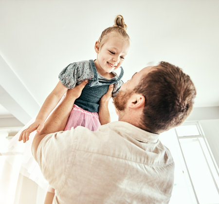 Family, children and a father carrying his girl daughter in the living room of their home together closeup. Smile, love or kids with a happy young child and her man parent having fun in their houseの写真素材
