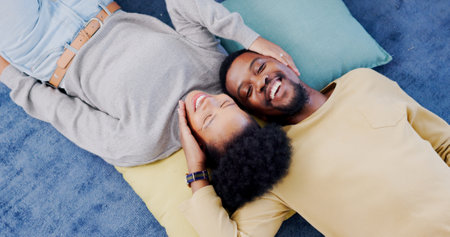 Top view, home and black couple with love, marriage and romance with bonding, relationship and relax together. Happy, African man or woman on the ground, hug or romantic with happiness, trust or careの写真素材