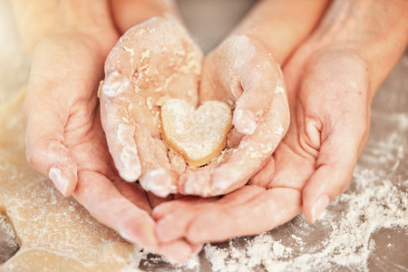 Hands, baking and heart with mother, kid and bonding together as daughter, learning or helping. Family, love and child development with quality time, baker and dough with skills, support and teachingの写真素材