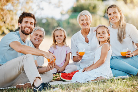 Park picnic, portrait and happy family children, parents and grandparents eating fruits, drink orange juice and enjoy outdoor nature. Love, grandpa and relax senior grandma, dad or mom bond with kidsの写真素材