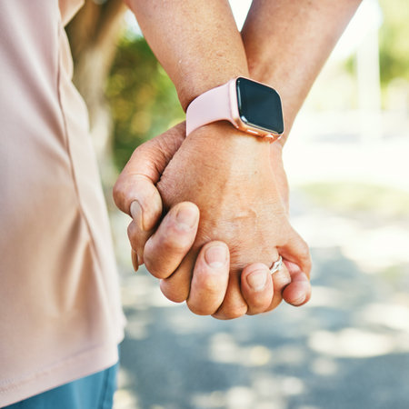 Closeup, holding hands and support with trust for love in bond, together or romance while walking. Elderly couple, man and woman in retirement with exercise for wellness, health or smart watchの写真素材