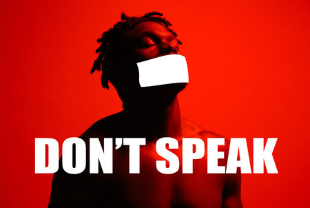 Speech censored, black man and tape on mouth in studio isolated on a red background. Cover, silence...