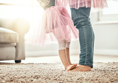 Ballet, feet and father with girl child in a living room with love, learning or dance in their home together. Family time, bond and legs of kid with parent in a house for support, care and securityの写真素材