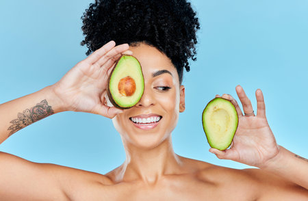 Skincare, avocado and happy woman in studio for cosmetic, wellness and treatment on blue background....