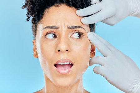 Beauty, plastic surgery and scared woman with hands on face in studio for cosmetic facial...