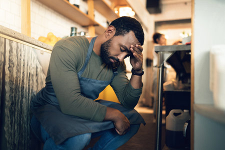 Waiter man, coffee shop and tired with stress, headache or regret for mistake, fail or fatigue at job. Barista person, burnout and pain in head with anxiety, mental health or depression in restaurantの写真素材