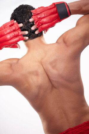 A finely tuned fighting machine. Rearview of a muscular boxer standing on a white background.