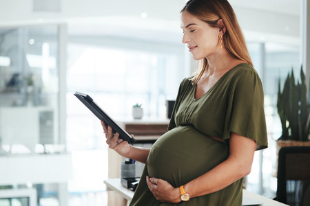 Tablet, smile and pregnant business woman in office reading research information on internet. Maternity, happy and female designer from Canada with pregnancy work on digital technology in workplace.の写真素材