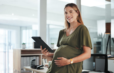 Portrait, tablet and business with a pregnant woman in her office at the start of her maternity leave from work. Company, smile and pregnancy with a happy young employee planning in the workplaceの写真素材