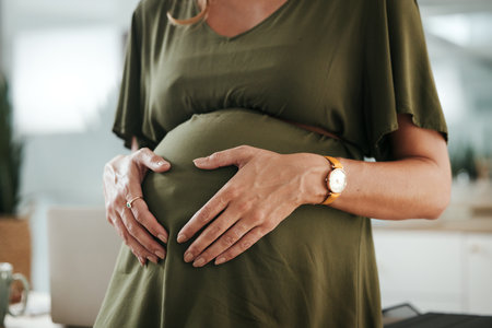 Hands, stomach and pregnant business woman feeling, massage and touch baby development, growth or belly. Abdomen, mother and closeup pregnancy person, worker or mom care, wellness and hope for futureの写真素材