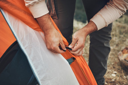 Hands, pitch tent and camping in nature on vacation, holiday or travel outdoor. Campsite, closeup and man set up shelter, tying and preparation for adventure, hiking or trekking in woods for freedomの写真素材