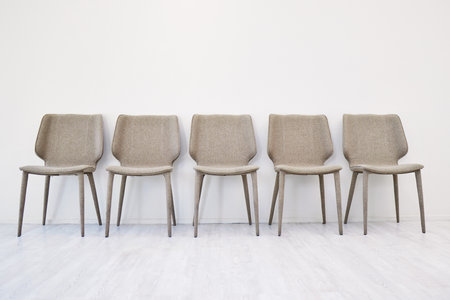 Interview, empty chair and waiting room by wall background in office and hiring for job. Human resources, furniture and seating area for recruitment, minimalist and advertising vacancy or positionの写真素材