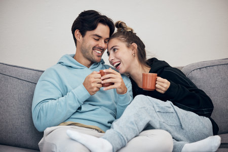 Couple, tea and relax with smile, love and trust on sofa in living room of home or apartment with bonding. Coffee, man and woman together with happiness for peace, romance and commitment on couchの写真素材