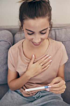 Pregnancy test, smile and woman on sofa in home, reading good news and check positive results....