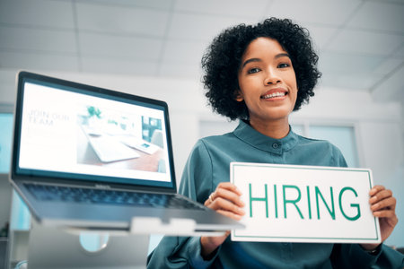 Woman with hiring sign, laptop and human resources with offer, recruitment and job opportunity at company. Onboarding, pc screen with website and HR invitation to join team, poster and recruitingの写真素材