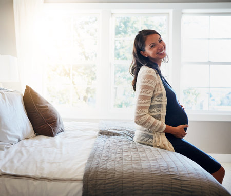 Home bed, happiness and woman pregnancy, massage stomach and mom happy for baby support, development or care. Expectation, bedroom flare and pregnant mother smile, love and relax on maternity leaveの写真素材
