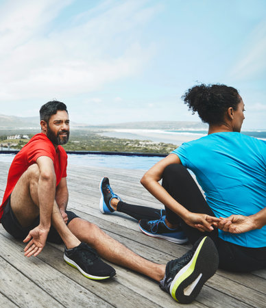 Stretching, legs and couple in exercise at beach to start fitness, training or outdoor on deck....