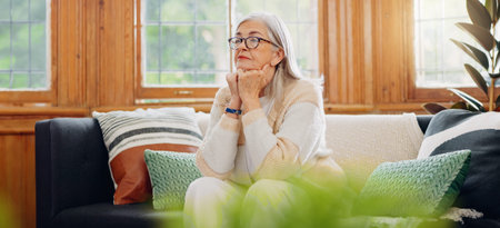 Thinking, reflection and senior woman on sofa in the living room with memory or dreaming face....