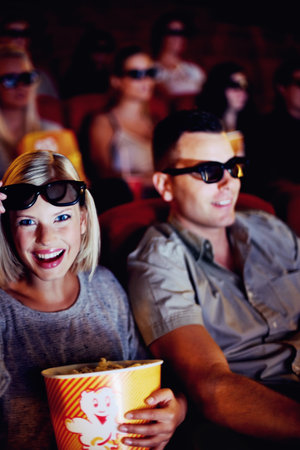 3d glasses, happy couple and popcorn, watching movie or eating on romantic date together. Cinema night, man and woman in film theater with snacks, eyewear and smile sitting in auditorium to relax.の写真素材