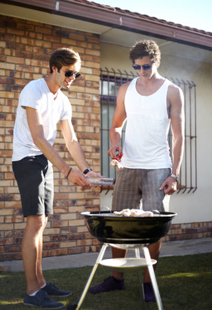Men, grill and meat season for BBQ in the backyard with cooking and lunch with friends. Garden, food and chat outdoor with young people together ready for eating with barbecue lunch in a yardの写真素材