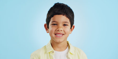 Face, boy child and smile in studio for wellness and confidence on a blue background with positive...