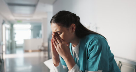 Stress, sad and loss with a woman nurse in hospital after a fail, mistake or error in healthcare treatment. Depression, anxiety and grief with a young medicine professional in a medical clinicの写真素材