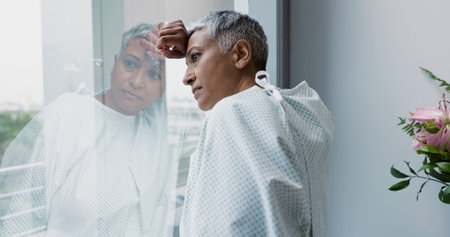 Sad, woman and thinking at window in hospital with stress, anxiety or fear of cancer, death or...