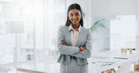 Business woman, portrait and smile with arms crossed in an office for confidence and career pride. Professional entrepreneur person from India at corporate company with positive attitude or happinessの写真素材