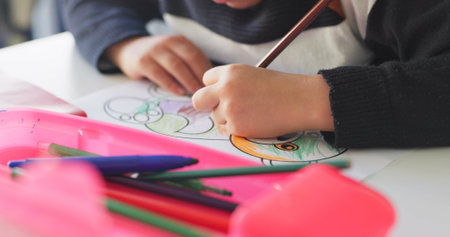 Creativity, school and hands of child drawing in a classroom for art lesson for education and development in class. Closeup, kindergarten and kid or student learning artistic homework on a deskの写真素材