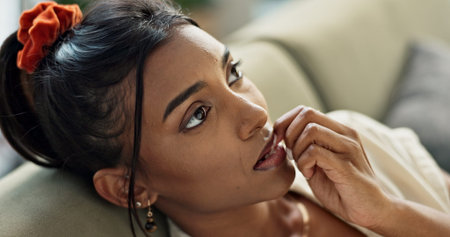 Thinking, anxiety and young woman on a sofa relaxing with an idea or memory in living room. Anxious,...