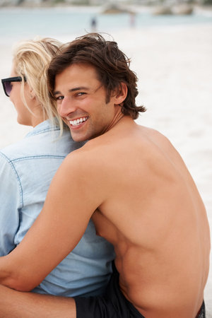 Couple, beach sand and sitting hug for holiday vacation, sunshine lovers or sea salt hair. Man, portrait and woman relax for partnership connection or ocean view, romantic or summer tropical travelの写真素材
