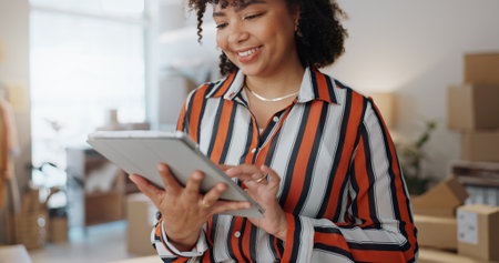 Businesswoman, smile and tablet in office for logistics, communication or email with warehouse. Fashion designer, distribution and parcel for customer order by transport, shipping or distributionの写真素材