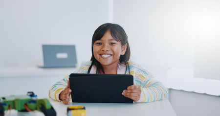 Smile, portrait and child in classroom with tablet, education and learning science with website. School, internet and face of happy girl with digital app for robotics, online research and technology.の写真素材