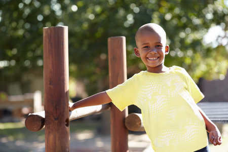African boy, portrait and playground at kindergarten, outdoor and sunshine for playing, games and freedom. Child, school garden or park with smile, happy and development in summer, nature or academyの写真素材