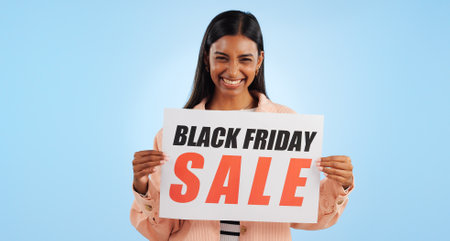 Black friday, poster and woman portrait with sale, discount and billboard in studio. Excited, smile and happy from savings and deal paper with banner and promo with blue background and price decreaseの写真素材