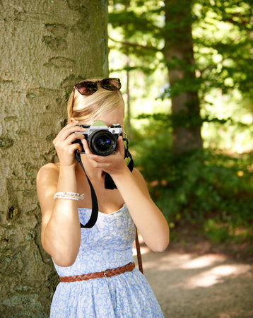Camera lens, nature and photographer with woman in forest for relax, memory and travel photography....