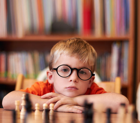 Portrait, chess and boy with glasses, bored and competition with training, skills and clear vision. Face, person or kid with eyewear, tournament or game with thinking, contemplation, ADHD or solutionの写真素材