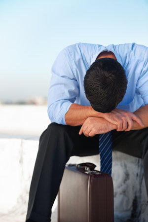 Business, man and outdoor with stress, depression and mental health with suitcase on rooftop in city. Professional, person or employee on roof of building with anxiety, risk and suffering with crisisの写真素材
