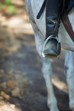 Boots, horse riding or jockey in countryside outdoor with rider or person for recreation or wellness. Exercise, travel or closeup of athlete with a healthy animal for training or support on farmの写真素材
