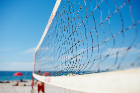 Volleyball, net and beach with blue sky outdoor for game, competition or match. Ocean, sports netting closeup or sand field for training, exercise and workout, fitness or sea for recreation in summerの写真素材