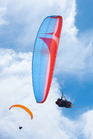 Sailing through the sky. two people paragliding on a sunny day.の写真素材