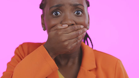 Black woman, hand over mouth with shock or surprise, drama or secret news with gossip isolated on pink background. Wow reaction for info, expression in portrait and alarm with fear in a studioの写真素材
