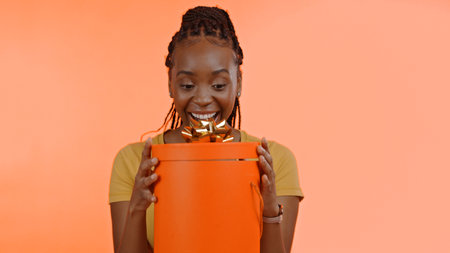 Birthday, present and black woman with surprise, box or gift in studio background or celebration. Wow, congratulations and excited winner of giveaway, package or product on offer for party and eventの写真素材