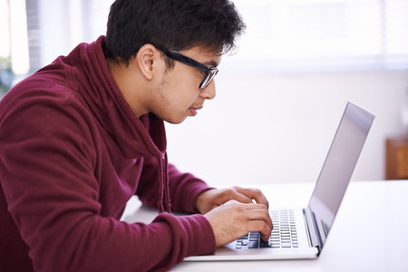 No distractions because Im hard at work. a handsome young man working on his laptop in an office.の写真素材